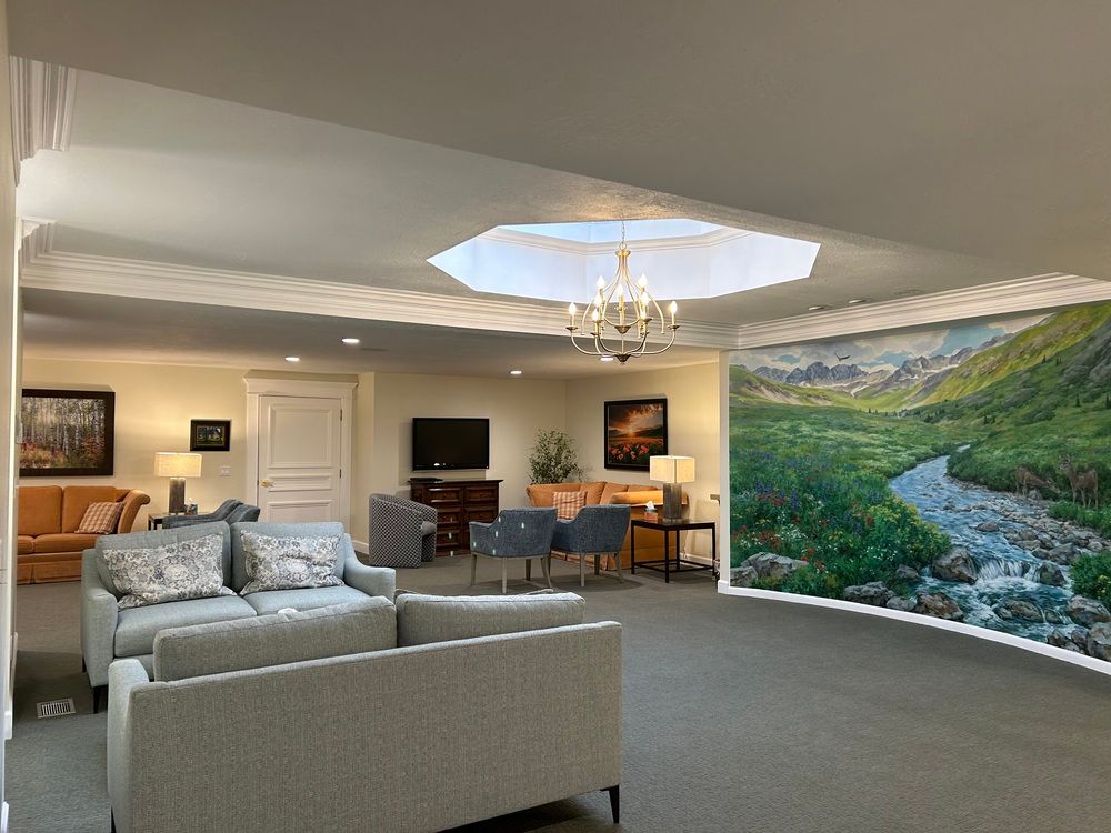 Spacious living room with gray sofas, a chandelier, and a large scenic mural on the wall