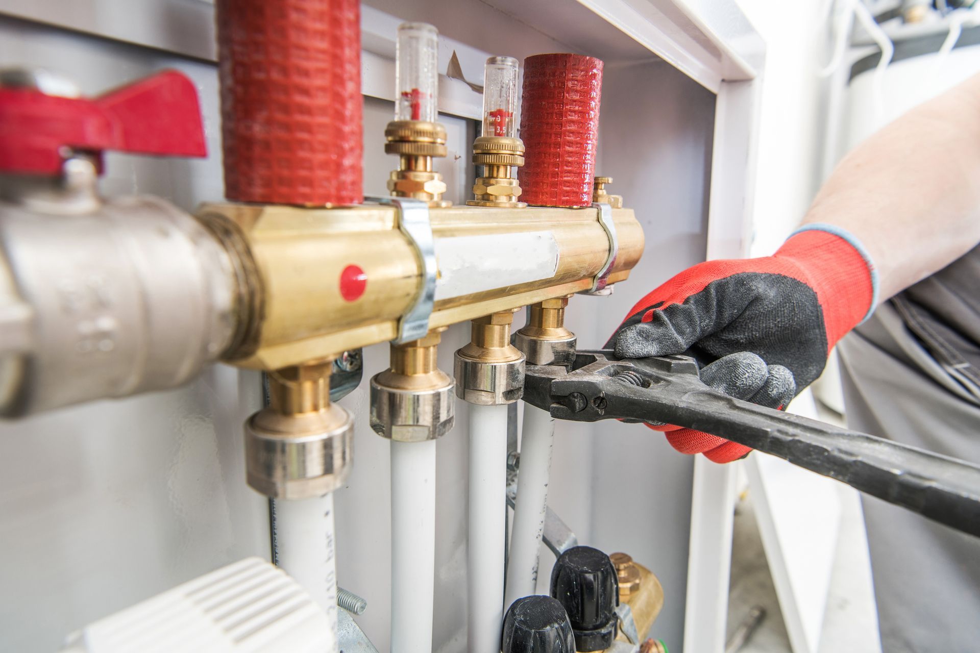 A plumber is working on a heating system with a wrench.