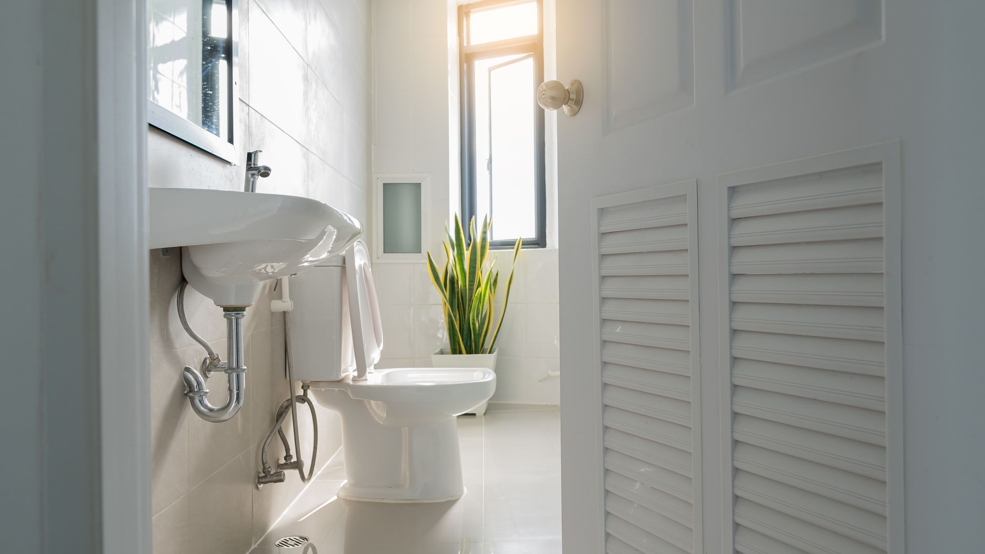 A bathroom with a toilet , sink and window.
