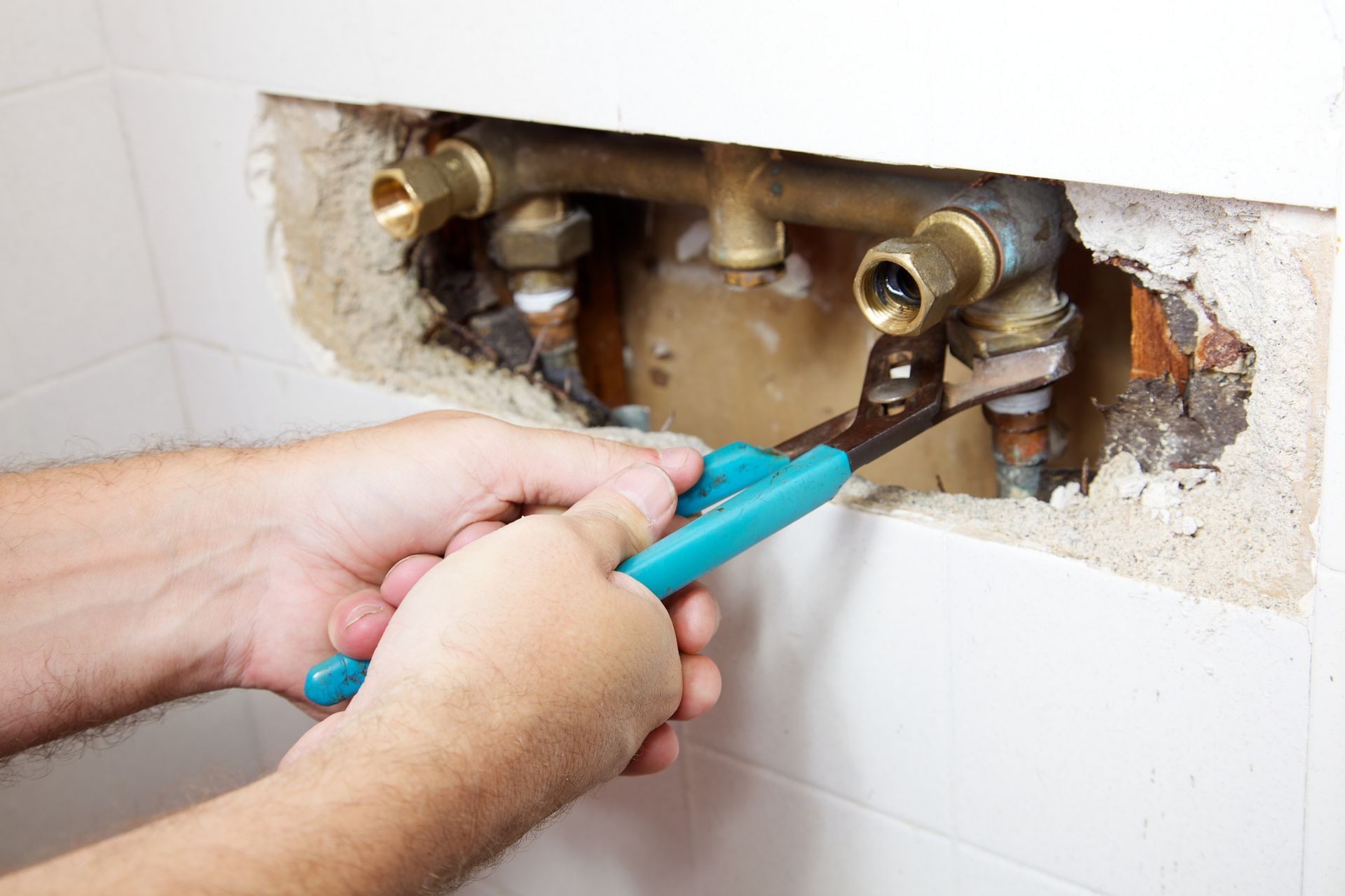 A person is fixing a pipe with a pair of pliers.