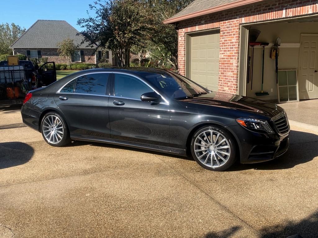 A black Mercedes Benz is parked in front of a garage.