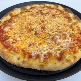 Cheese pizza baking on a black pan, golden crust and melted topping