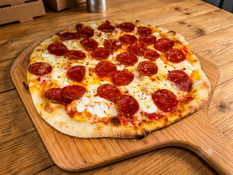 Pepperoni pizza on a wooden cutting board on a kitchen counter