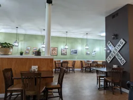 Rustic restaurant dining room with wooden tables, chairs, mint green walls, and a central white support column