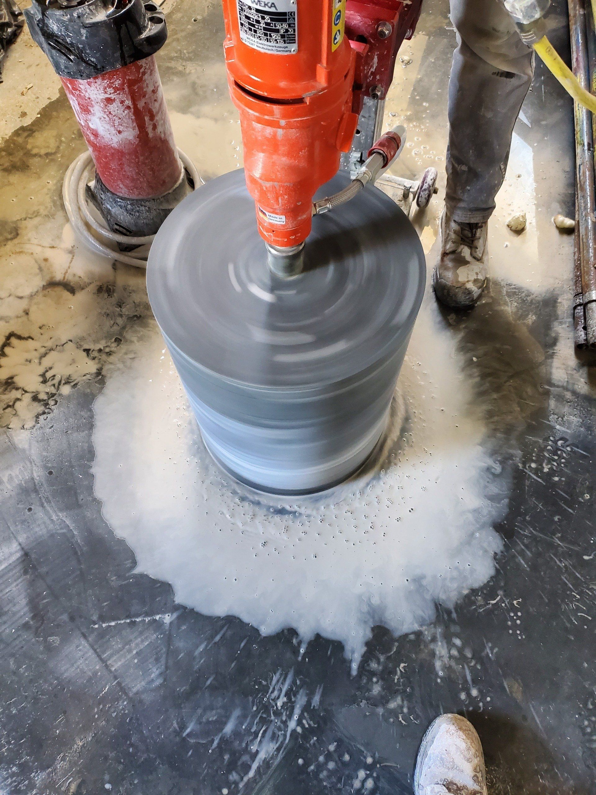 A person is using a drill to drill a hole in a concrete floor.
