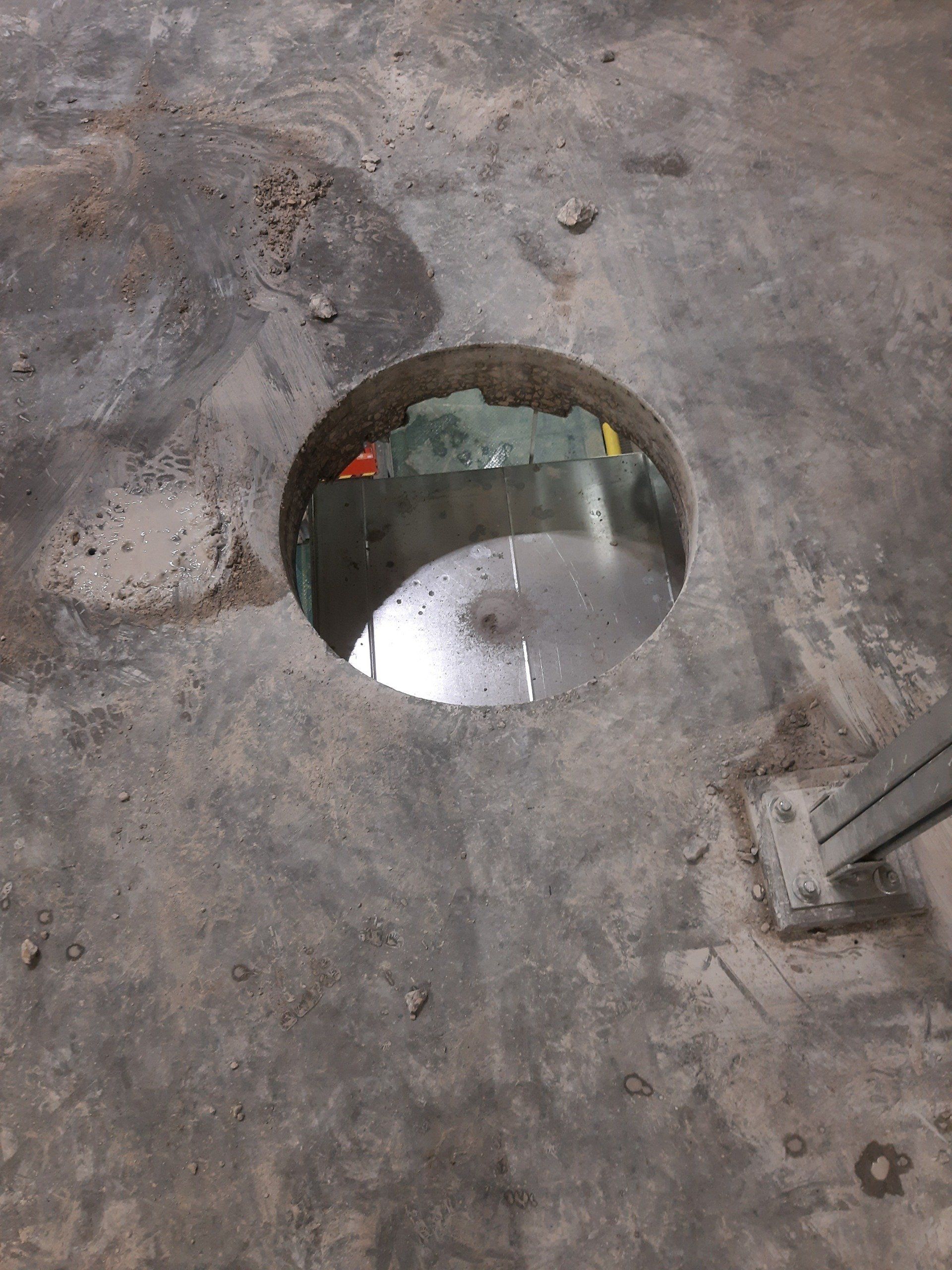 A hole in the floor with a metal object in it.