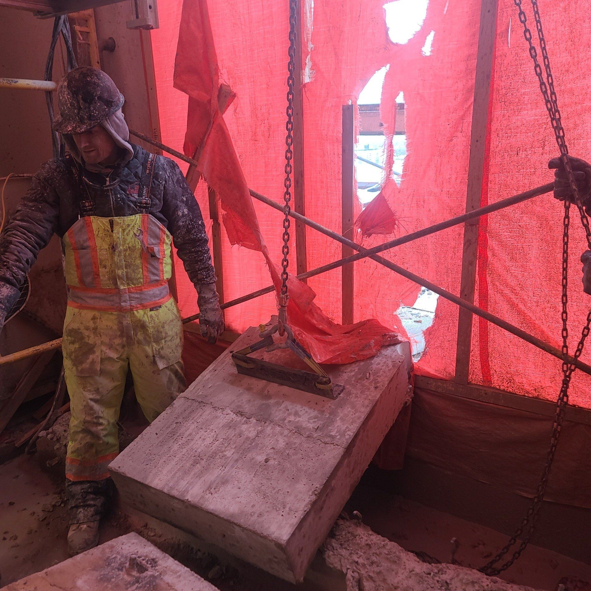 A man in overalls is standing in front of a red tarp