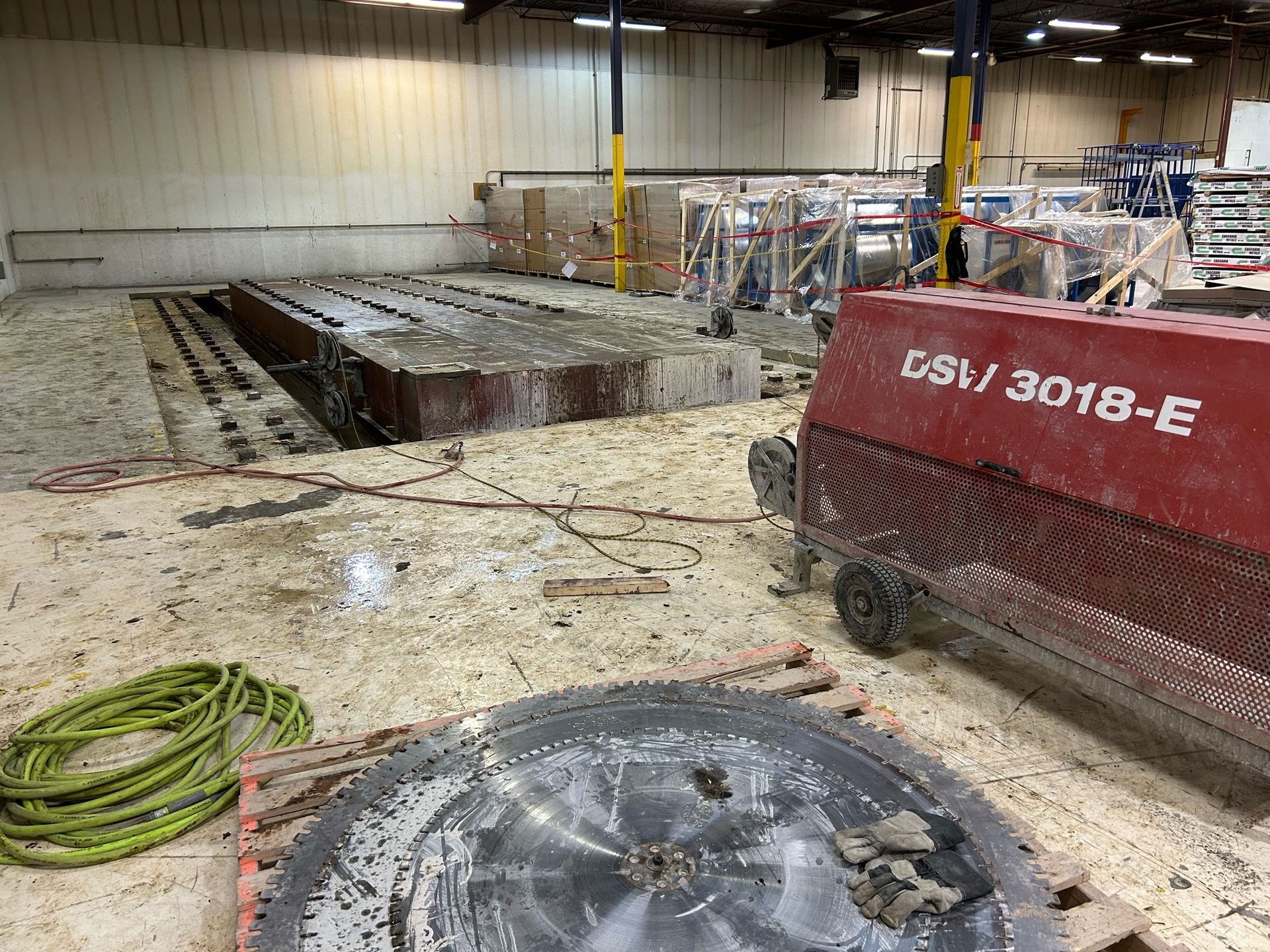 Concrete saw cutting floor. Saw and equipment in a warehouse setting.