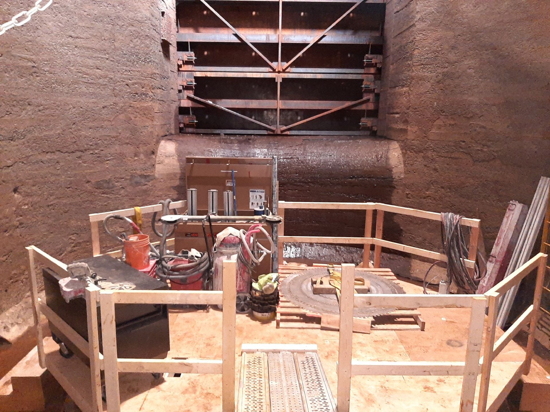 Interior of a construction site. Wooden safety rails enclose tools and equipment in a tunnel.
