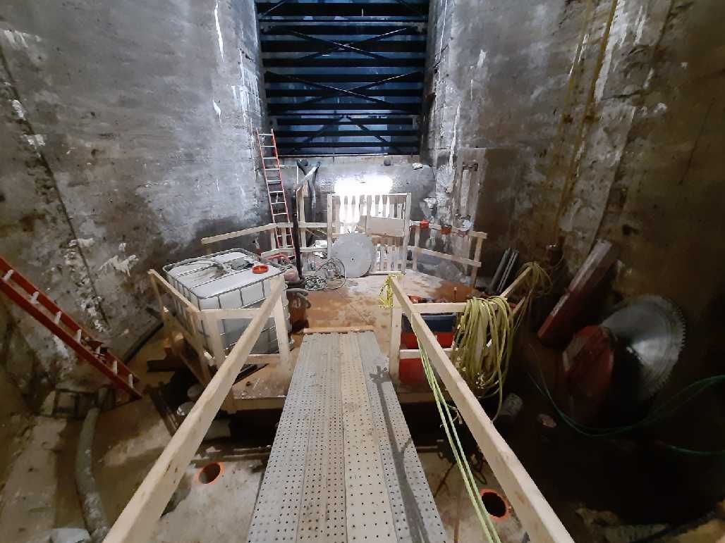 Tunnel under construction, with wooden walkways and tools.