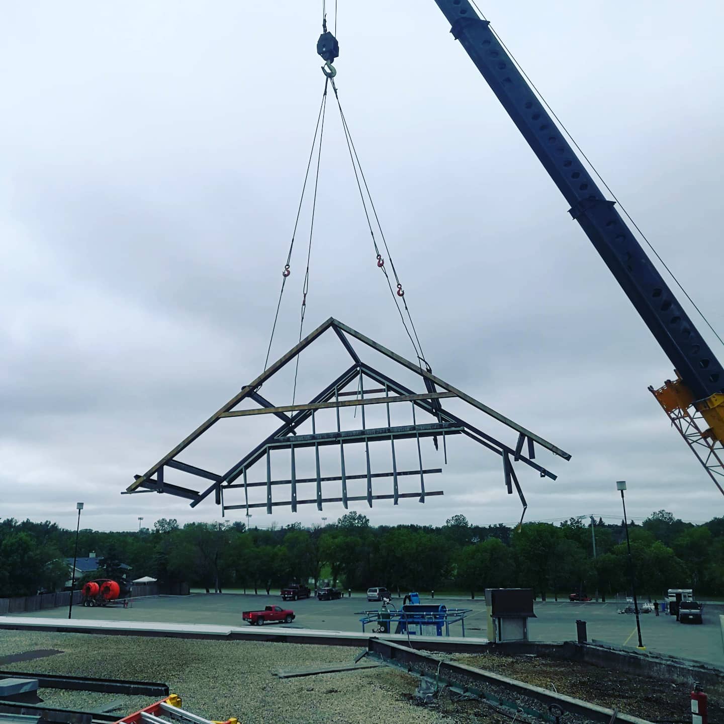 A crane is lifting a piece of wood in the air