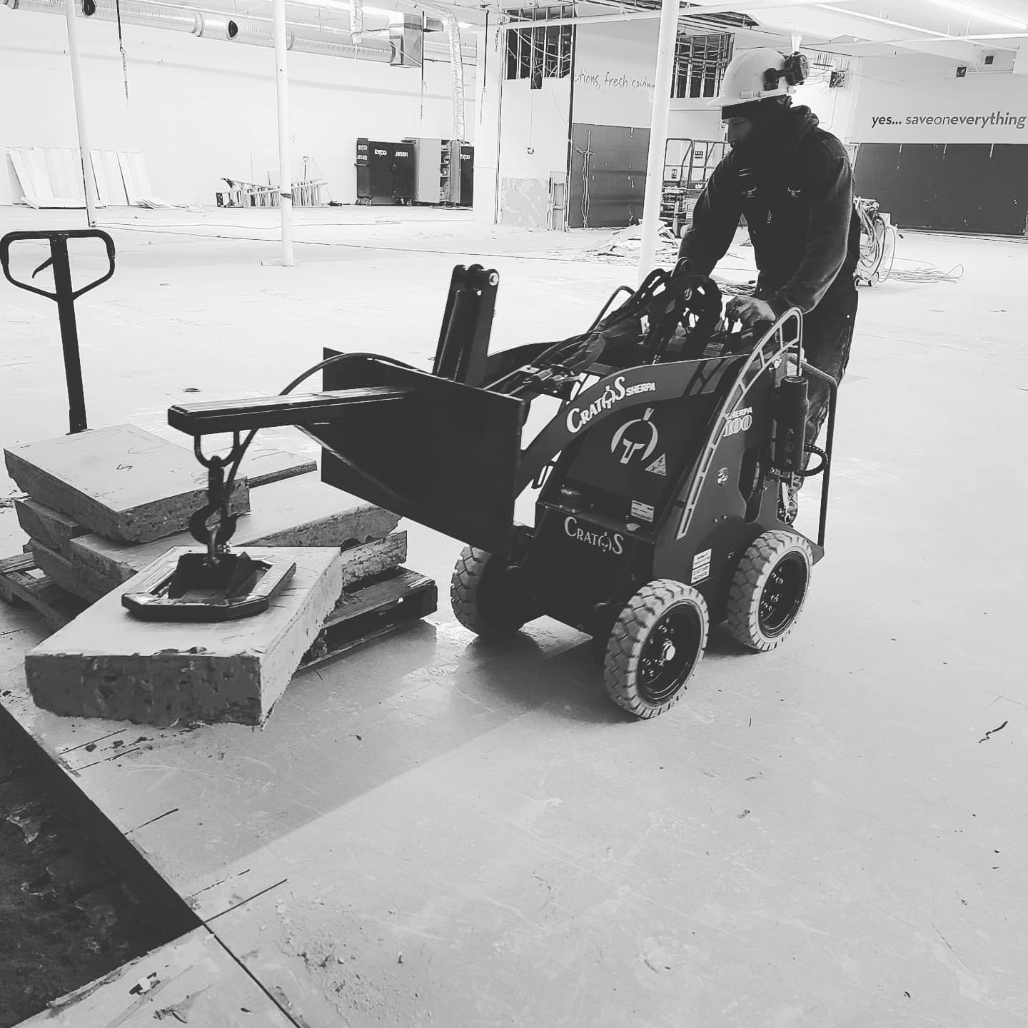 A man is driving a small tractor in a building.