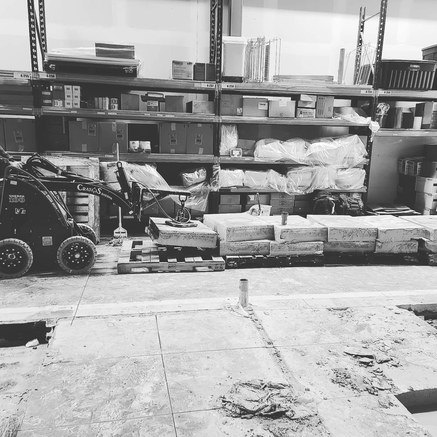 A black and white photo of a warehouse with shelves and pallets
