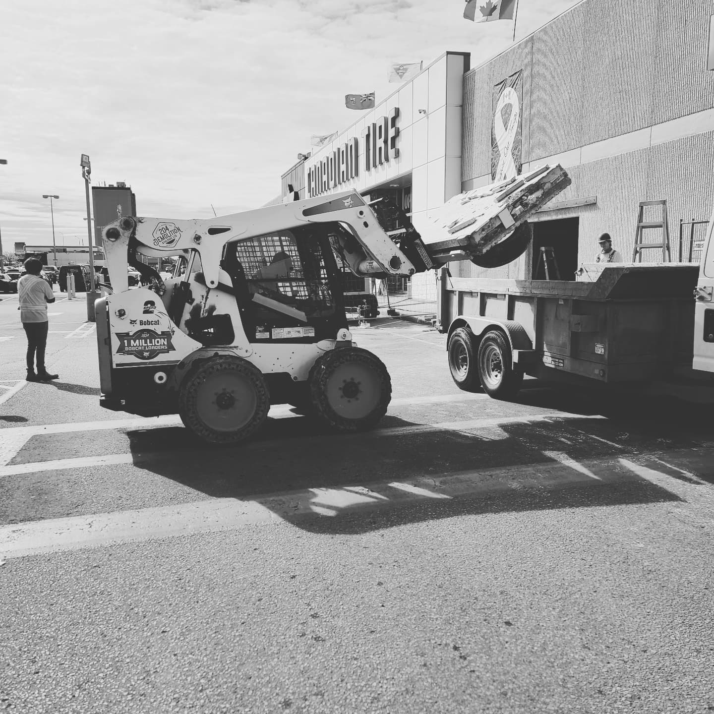 A black and white photo of a construction vehicle parked in front of a store