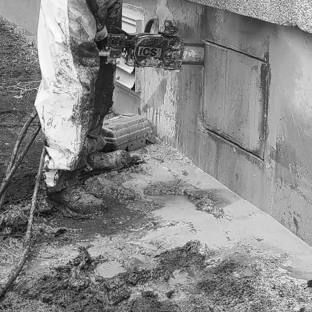 A man is cutting a hole in a wall with a chainsaw.