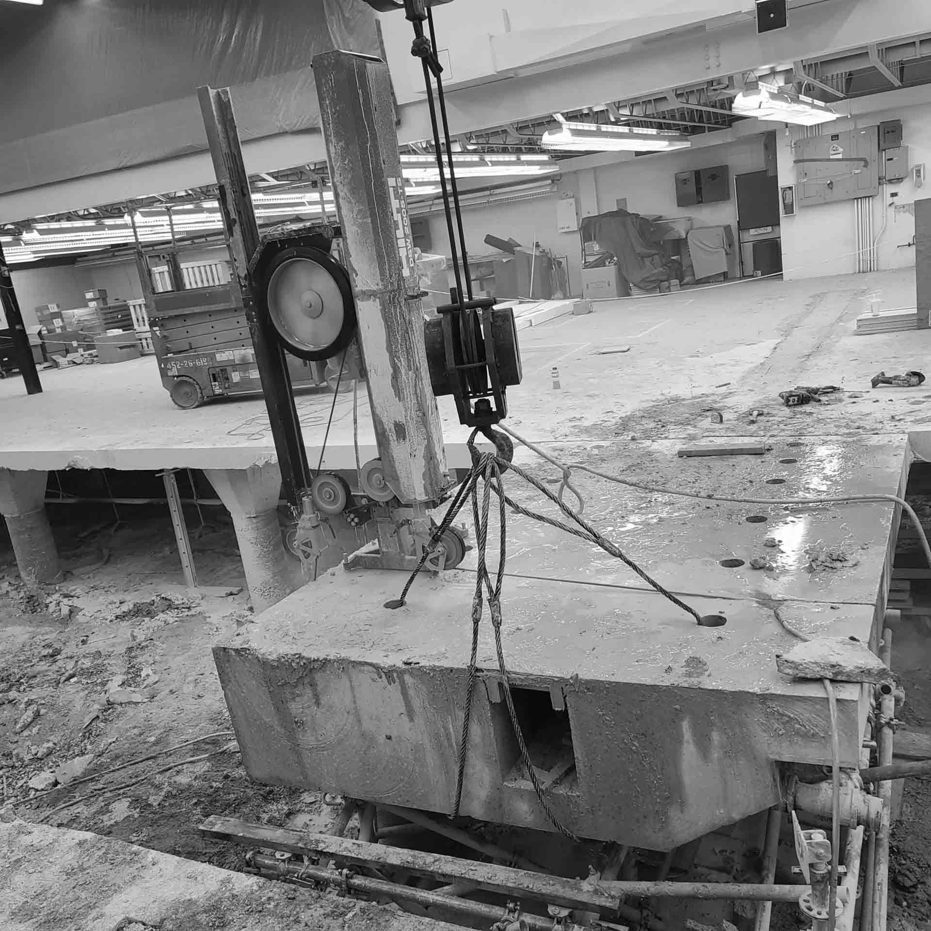 A large concrete block is being lifted by a crane in a black and white photo