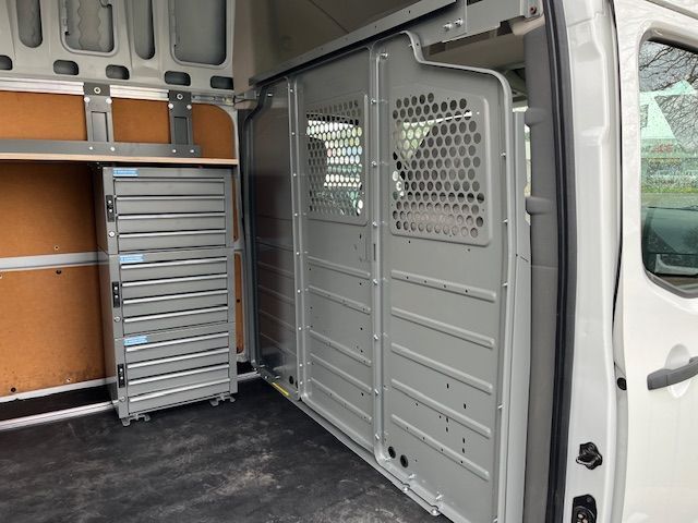 The inside of a white van with a cage on the side of it.