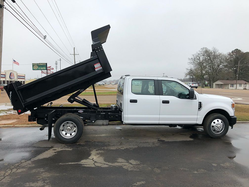 A white dump truck is parked on the side of the road.