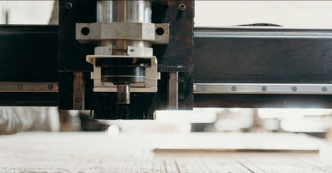 A machine is cutting a piece of wood on a table.