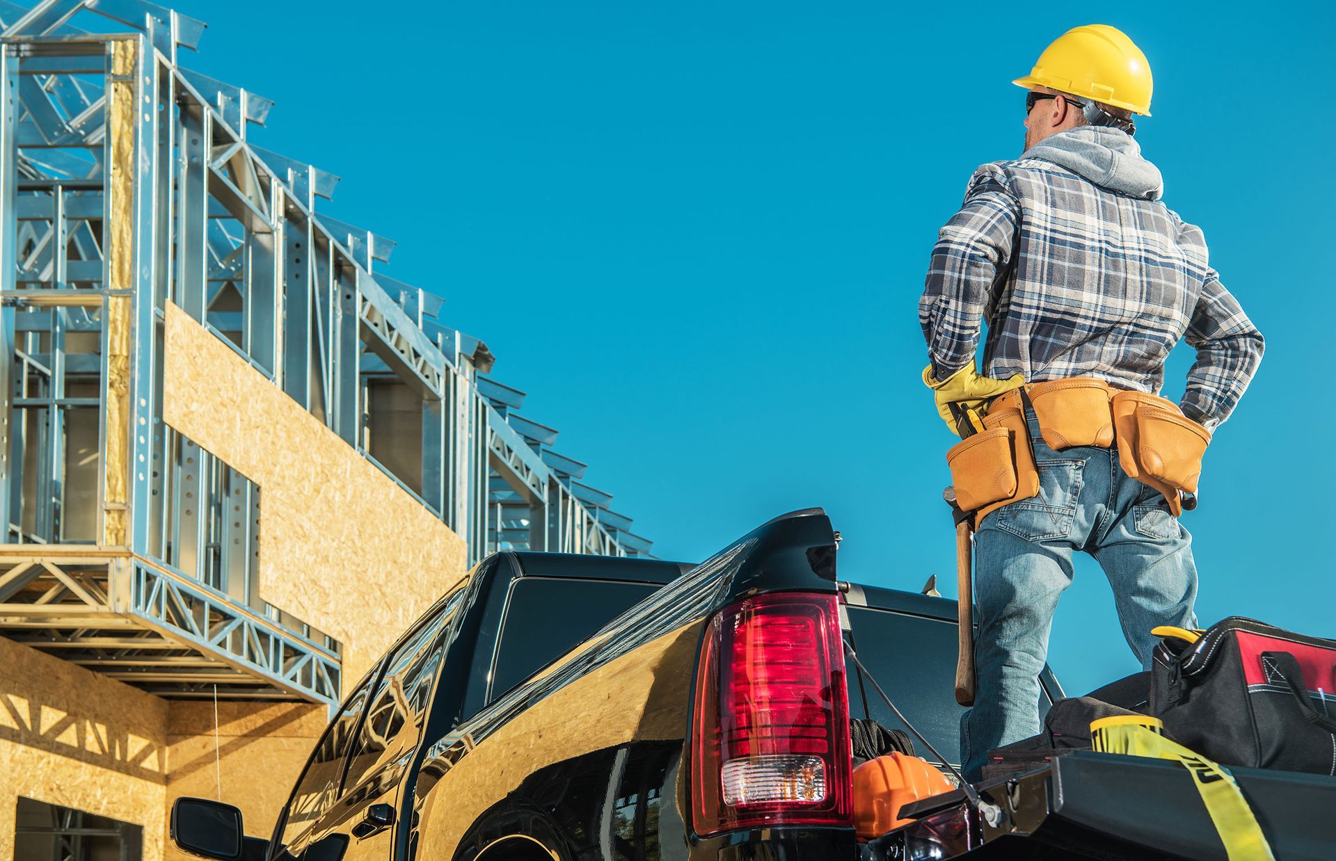 A construction worker is standing on the back of a truck