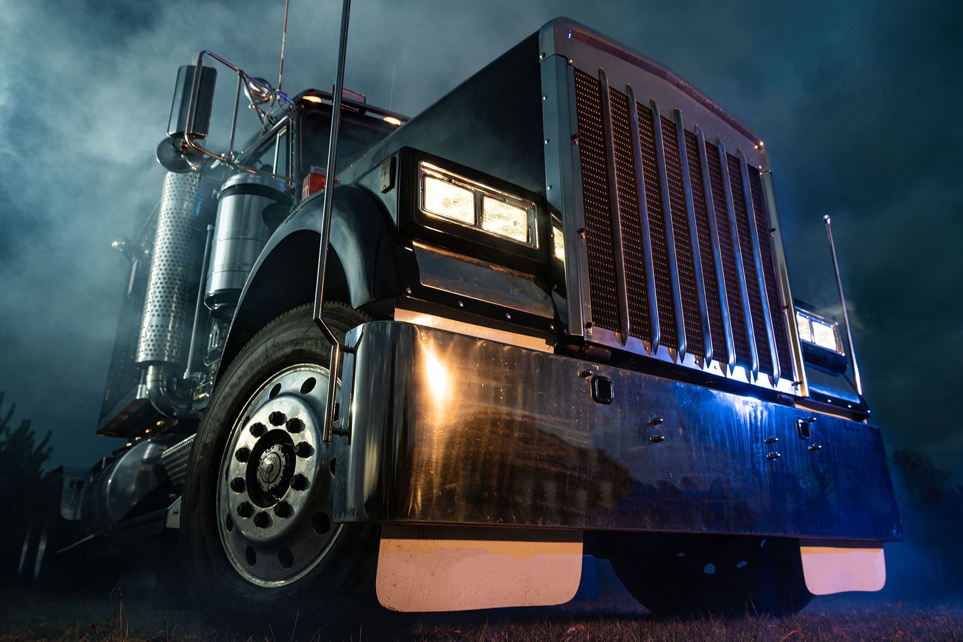 A large semi truck is parked on the side of the road at night