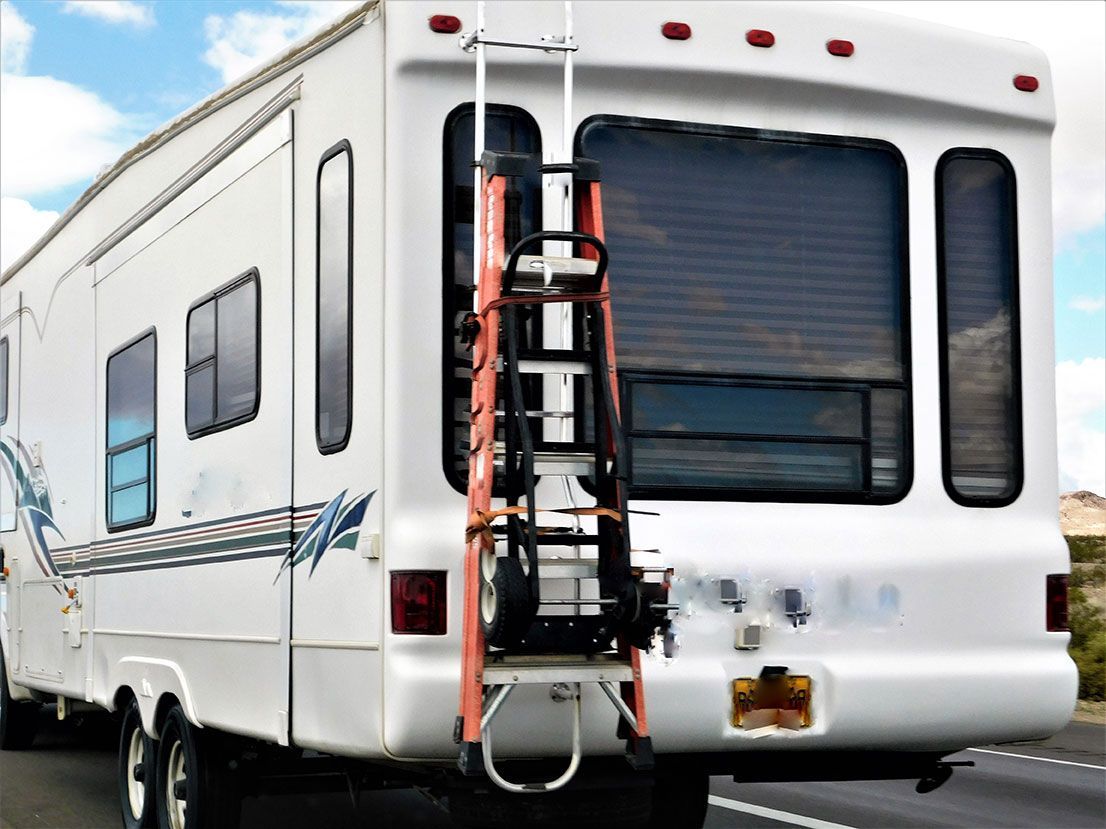 A white rv with a ladder attached to the back of it