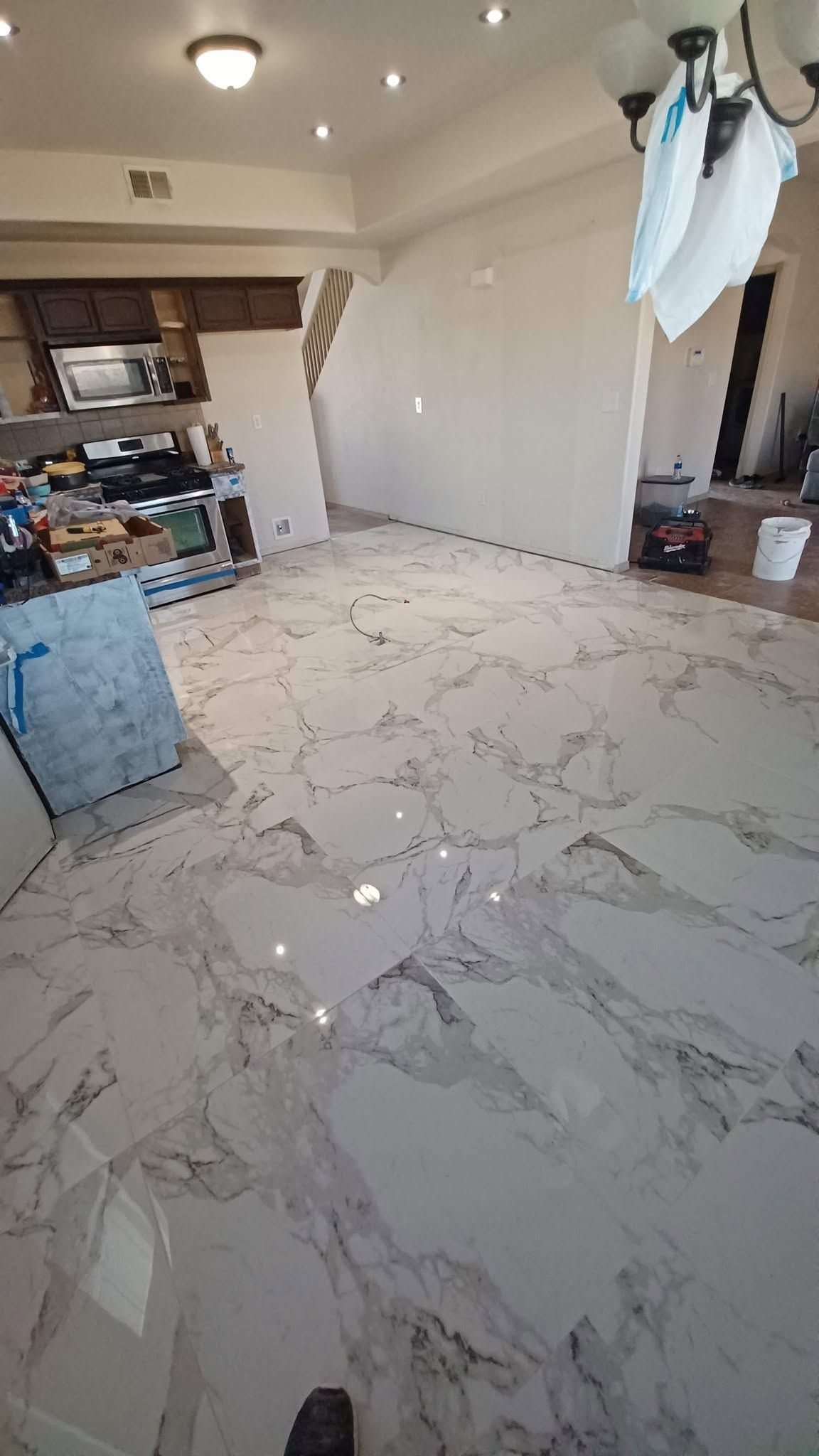 Empty living room with glossy marble floor, white walls, ceiling light, and scattered items near a window.