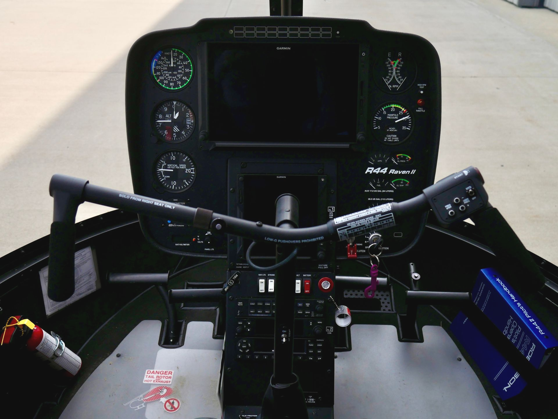 A small black helicopter is parked on a runway.