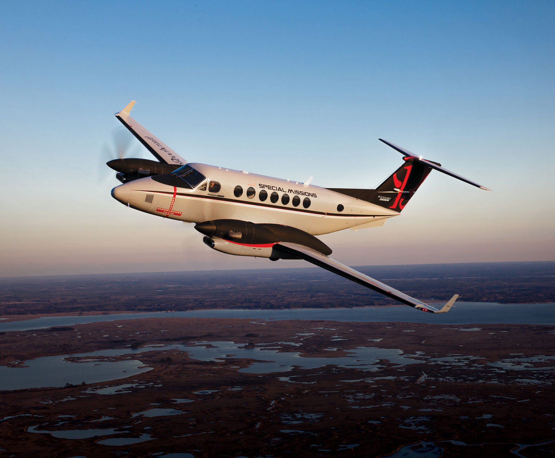 A small propeller plane is flying over a body of water