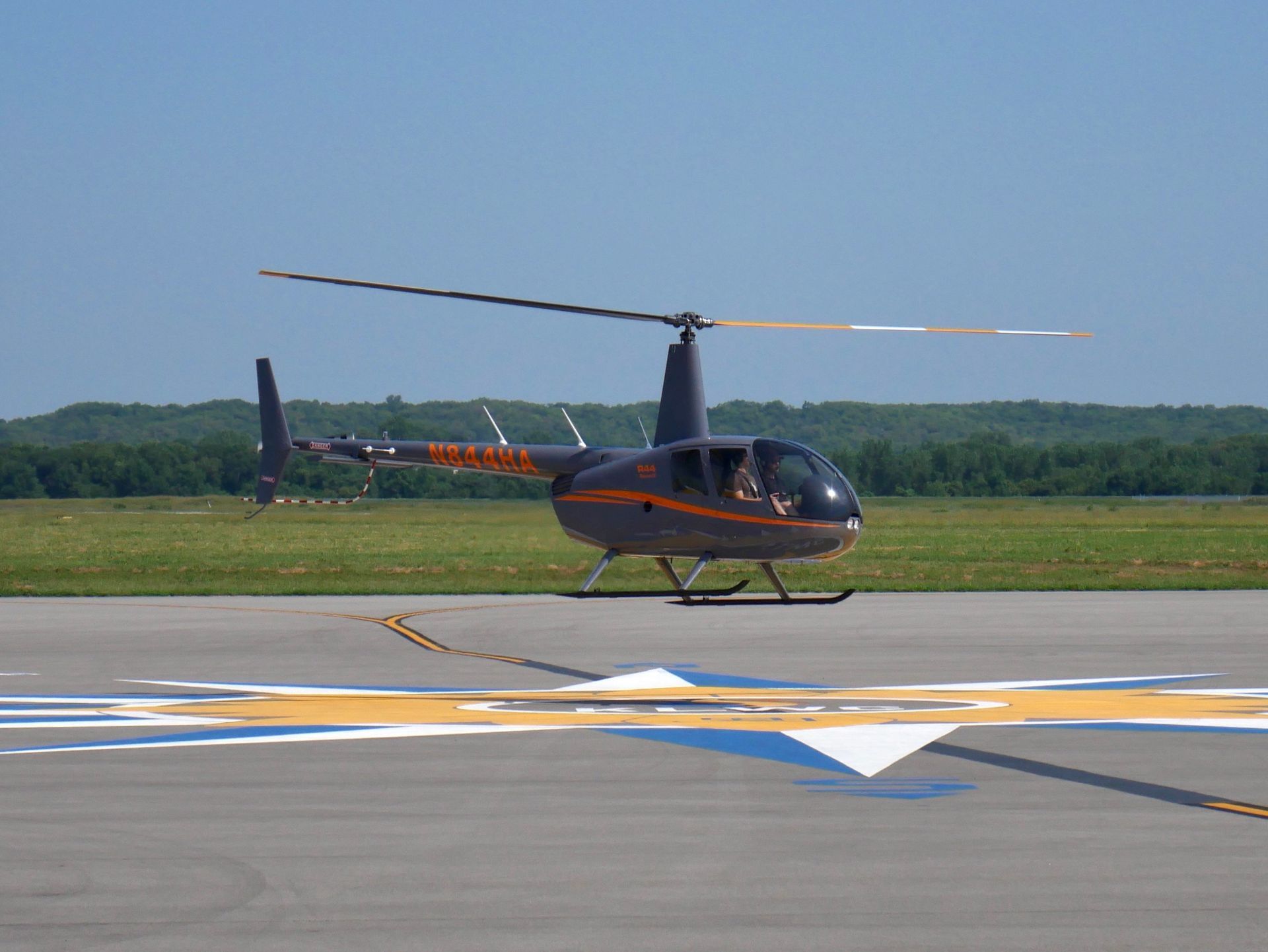 Black helicopter in flight against a blue sky, with white registration number and landing skids.