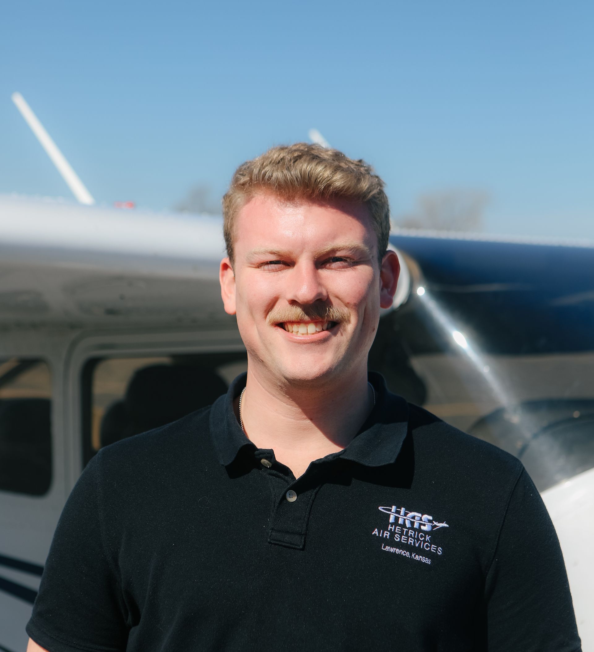 A man is standing in front of a small airplane.