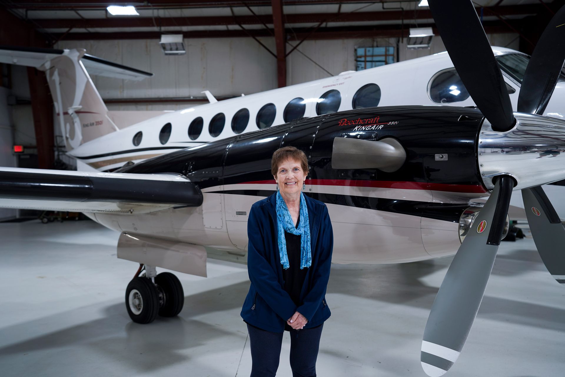 A woman is standing in front of an airplane in a hangar.