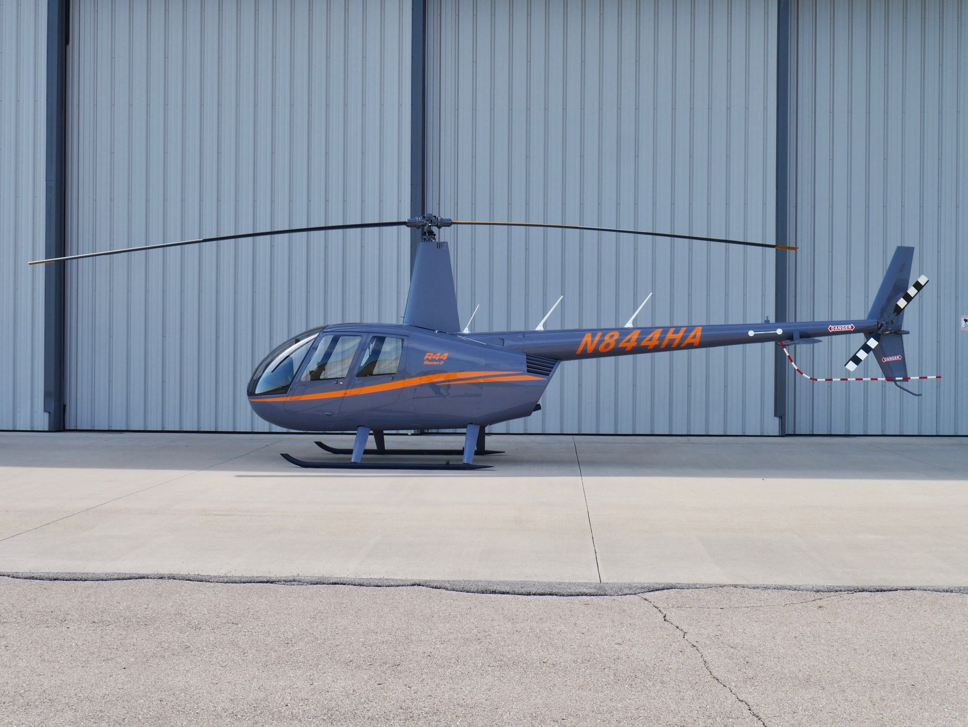 Black helicopter in flight against a blue sky, with white registration number and landing skids.