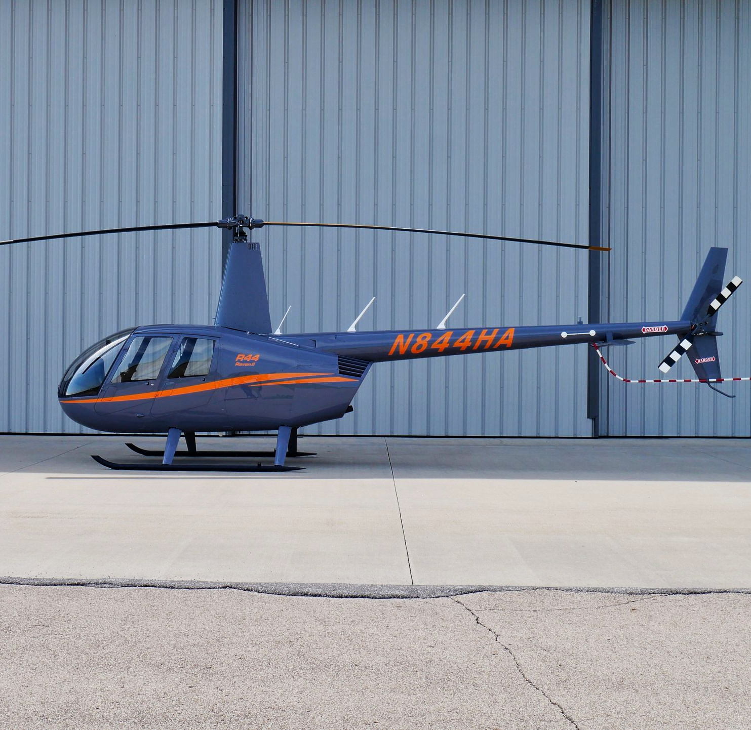 A small black helicopter is parked on a runway.