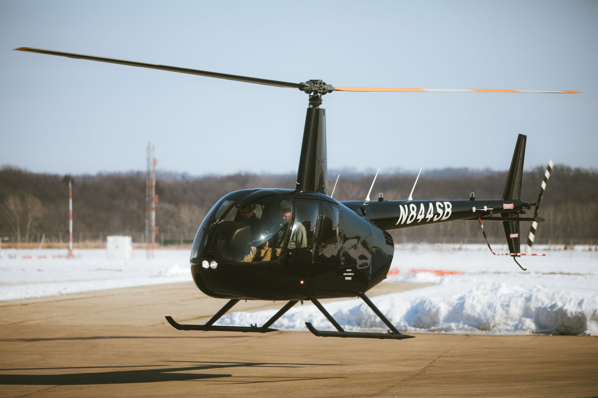 A black helicopter is sitting on a runway in the snow.