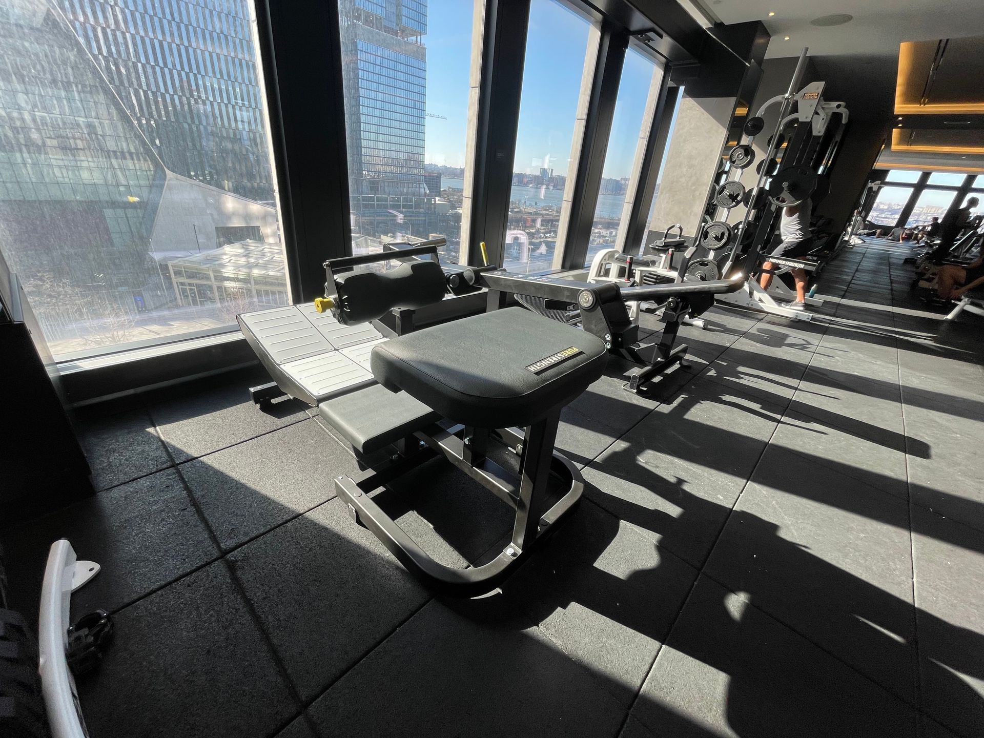 Fitness equipment being set up in a high-rise gym with city views through large windows.