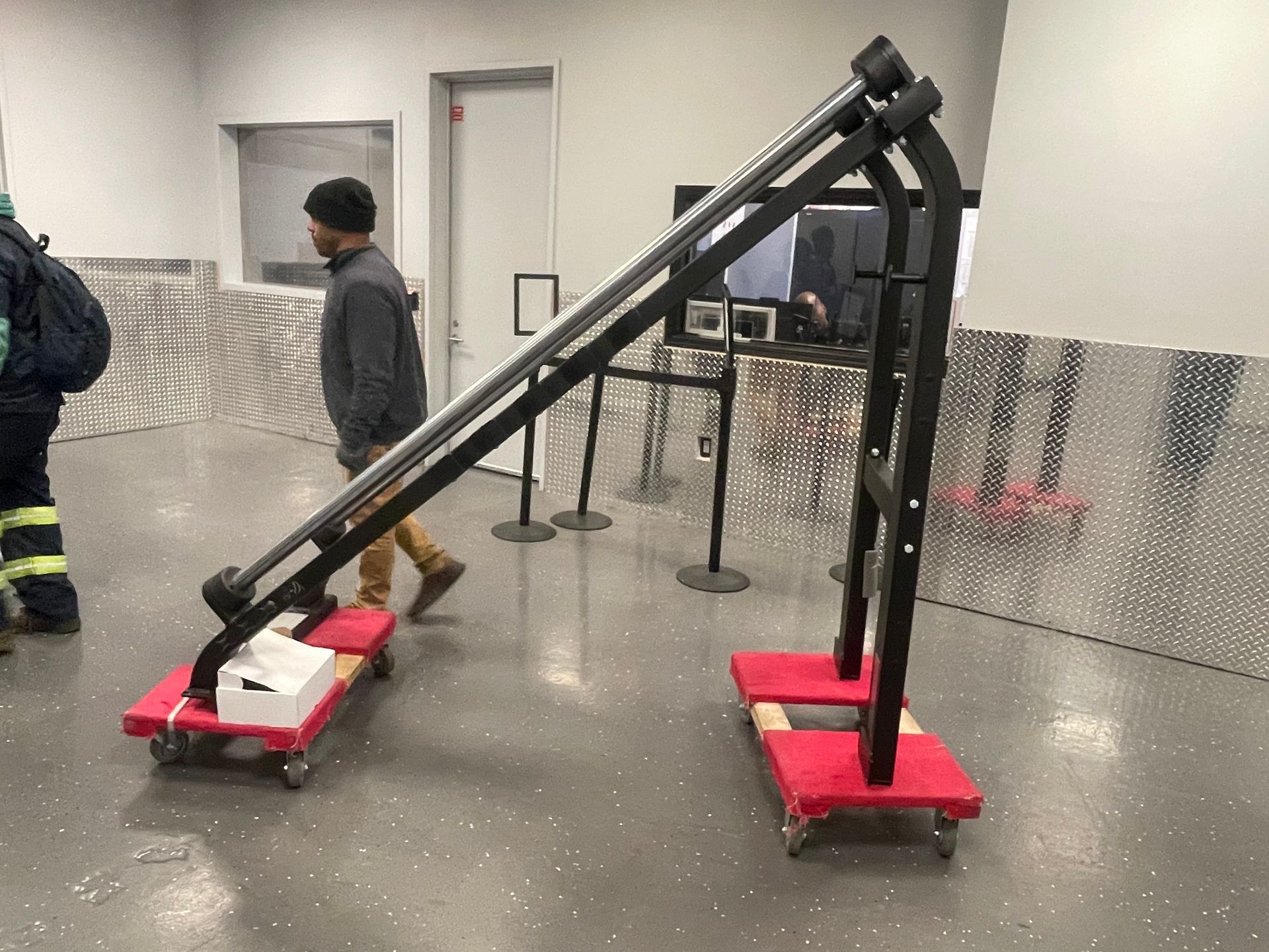 Workers moving large fitness machine on a dolly through a loading area.
