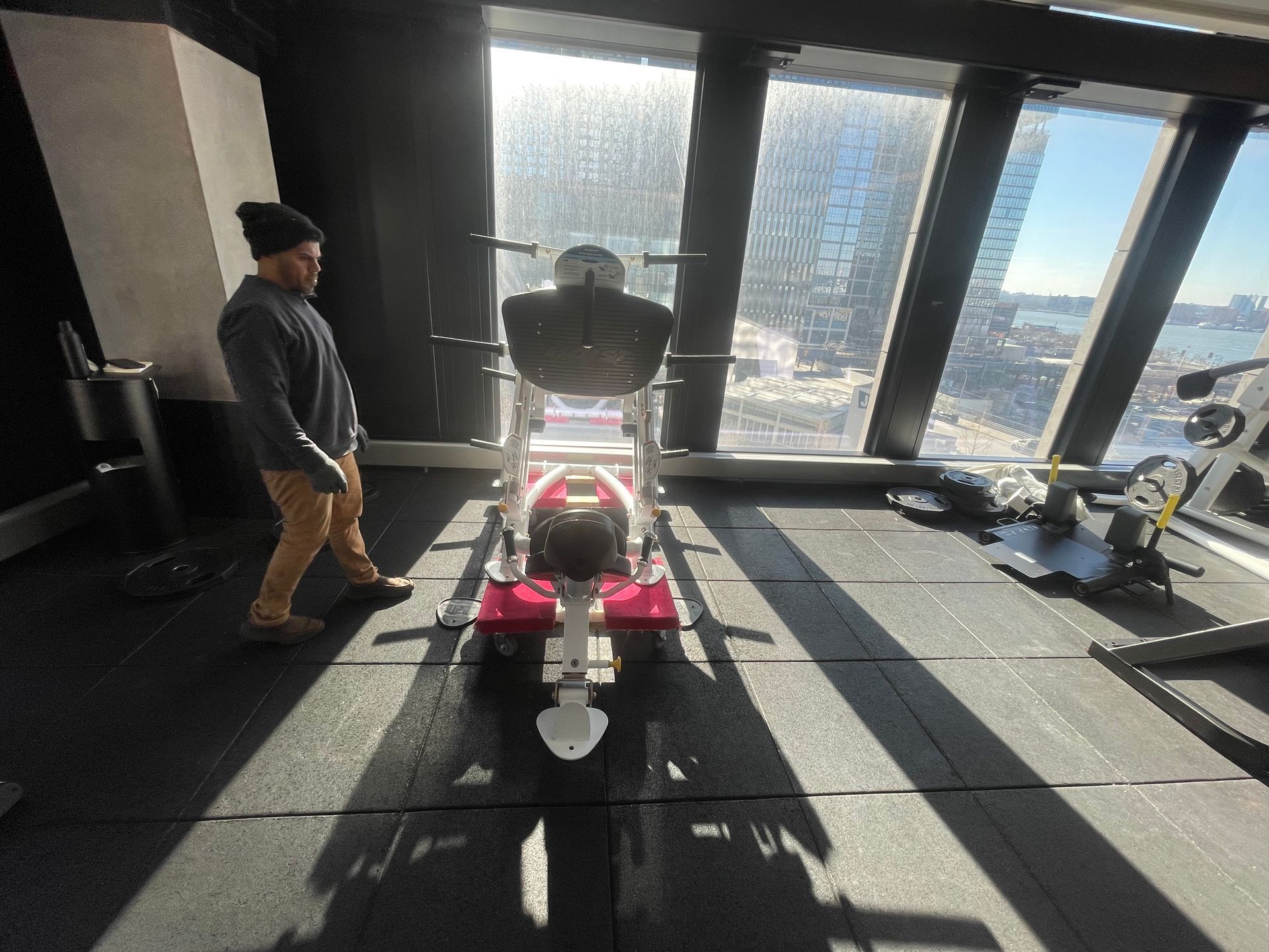 Technician preparing gym equipment for installation in a high-rise fitness center.