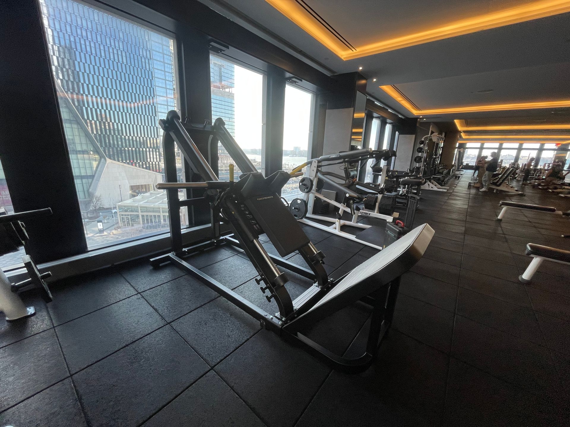 Completed gym setup with leg press machine and other equipment in luxury high-rise fitness center.