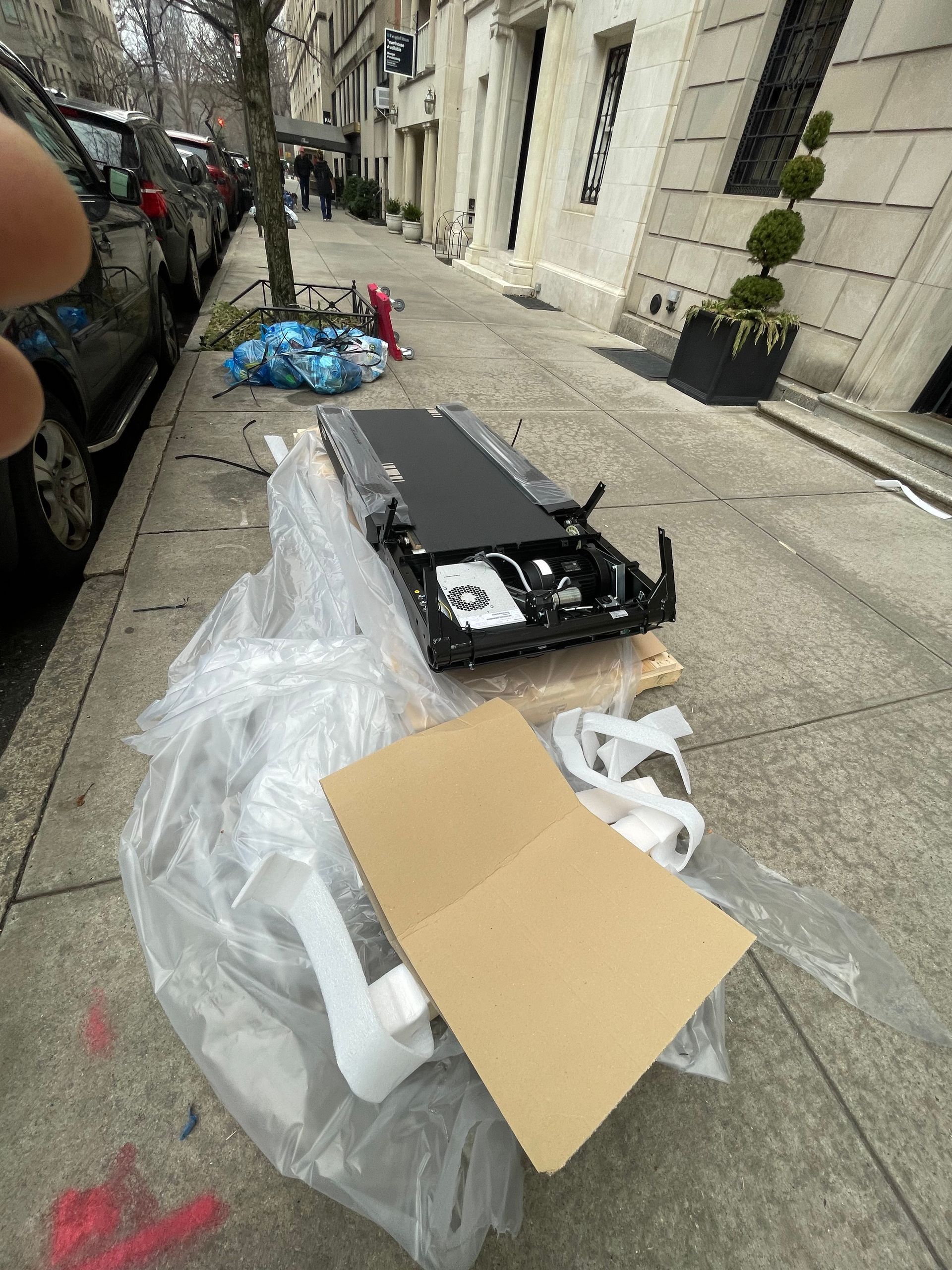 Gym equipment parts and packaging materials laid out on the sidewalk before delivery.