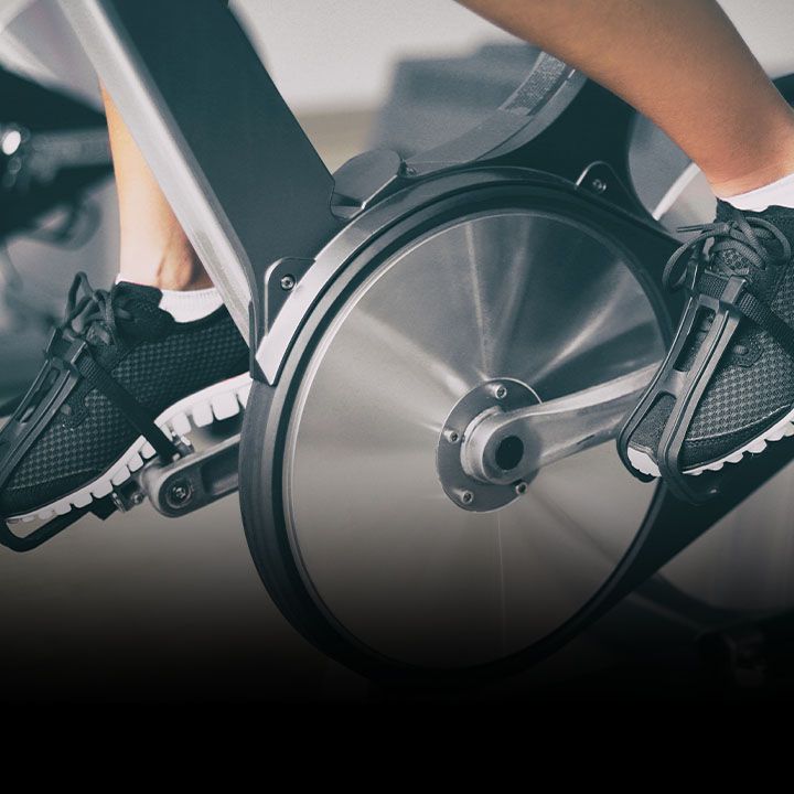 Close-up of a person cycling on gym bike promoting Service King exercise bike services