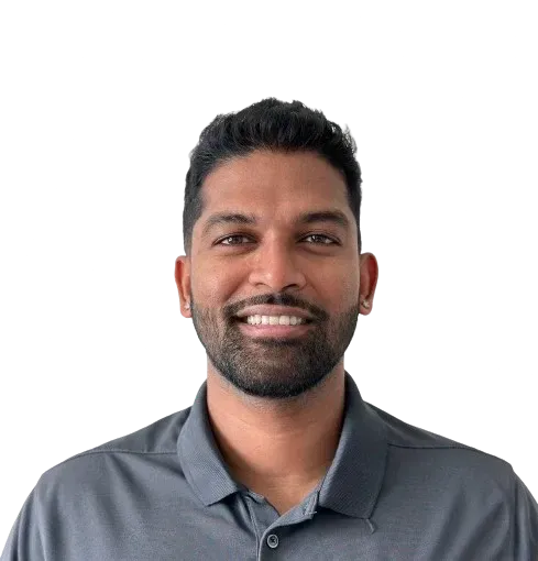 Smiling man with dark hair and stubble, wearing a gray collared shirt.