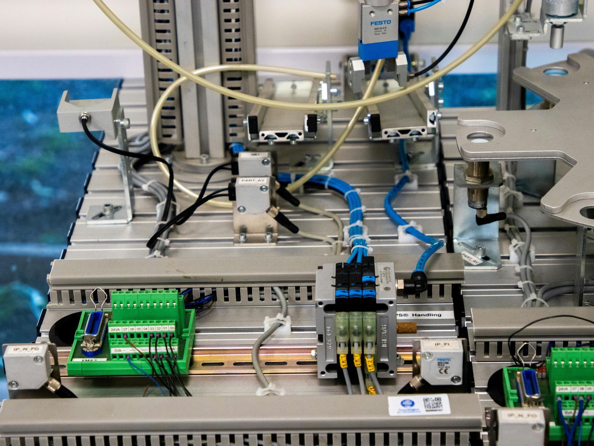 Close-up of industrial automation equipment with pneumatic tubes, wiring, and electronic components.