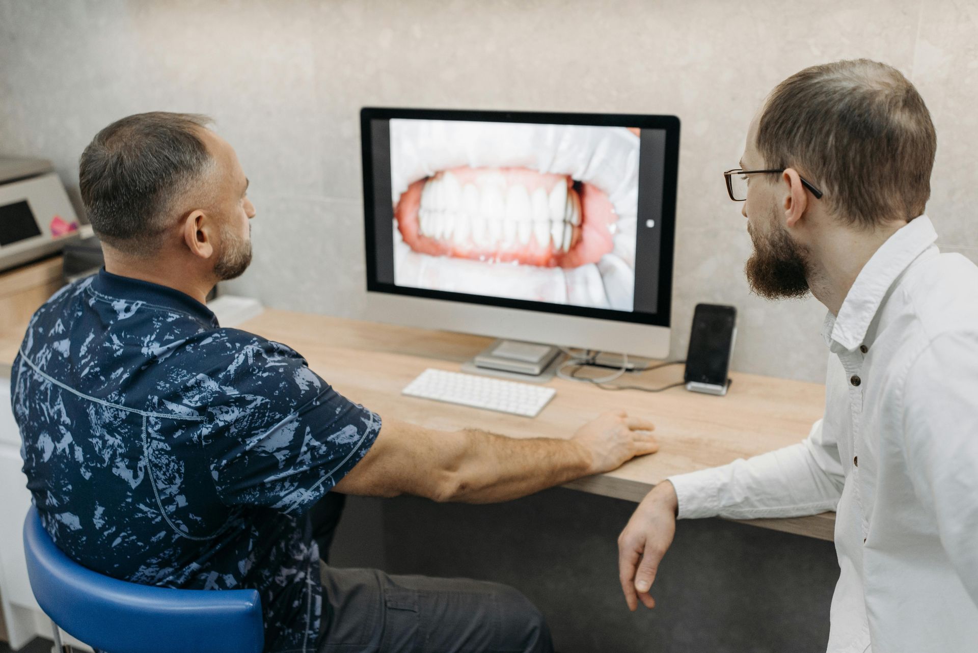 Two men looking at a monitor displaying a close-up dental view, possibly a dentist and patient.