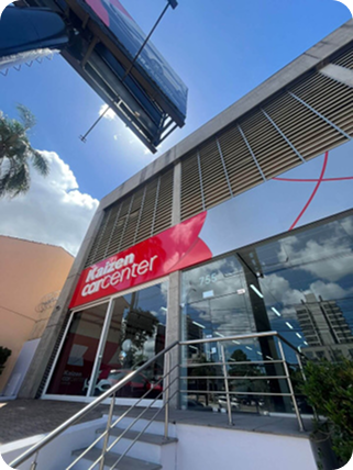 Exterior do Kalízen Carcenter, com um logotipo vermelho, janelas de vidro e uma escada sob um céu ensolarado.