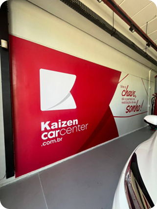 Adesivo de parede com o logotipo da Kaizen Carcenter em vermelho e branco, ao lado de um carro branco.