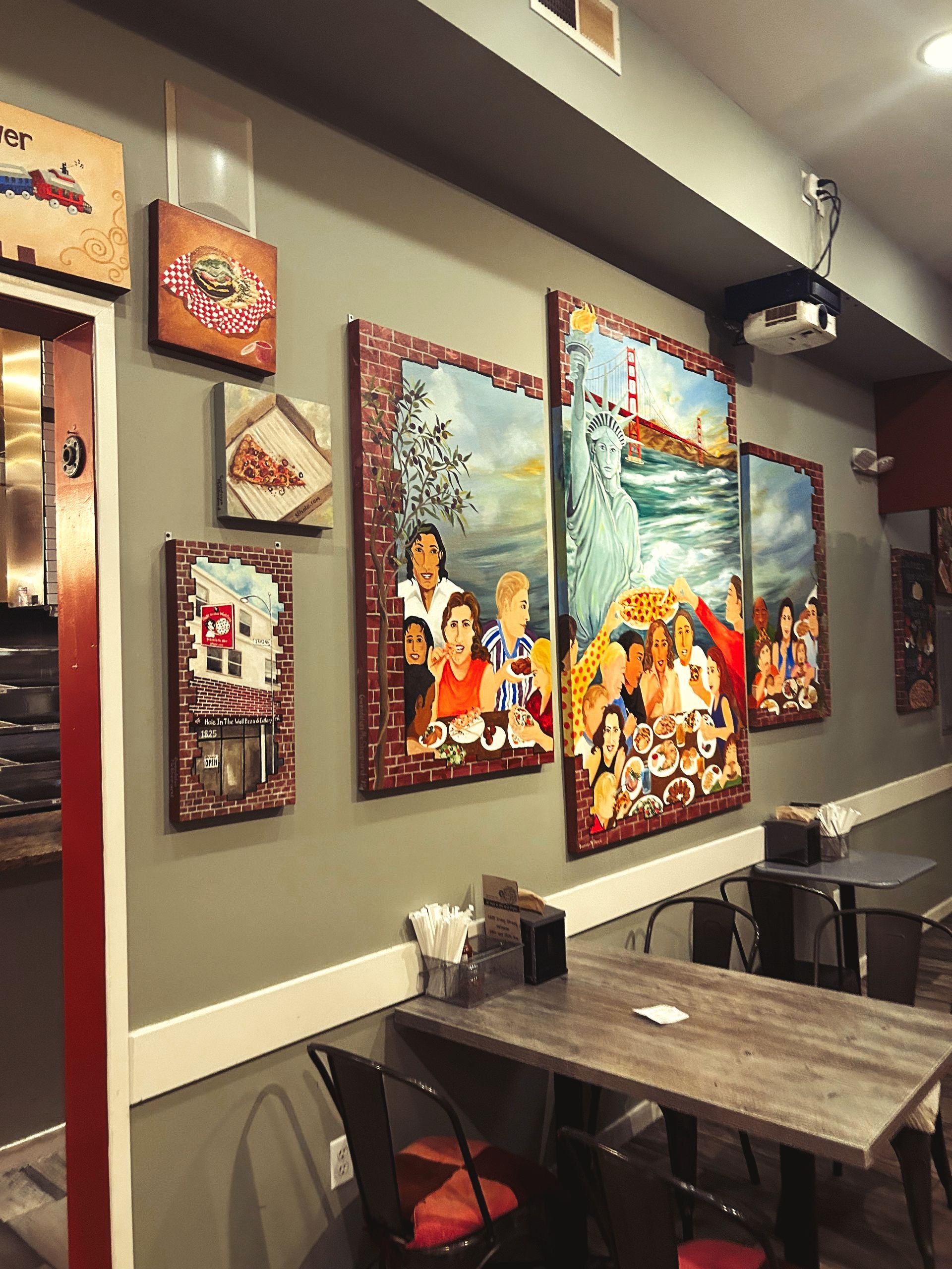 a restaurant with tables and chairs and paintings on the wall