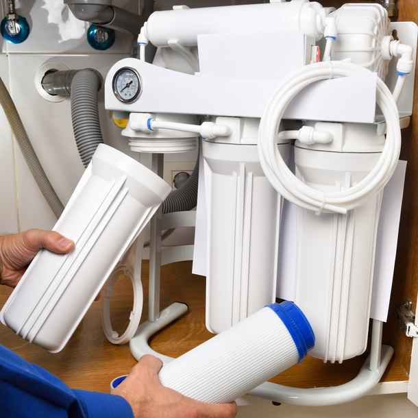 A man in a blue shirt is working on a water filter