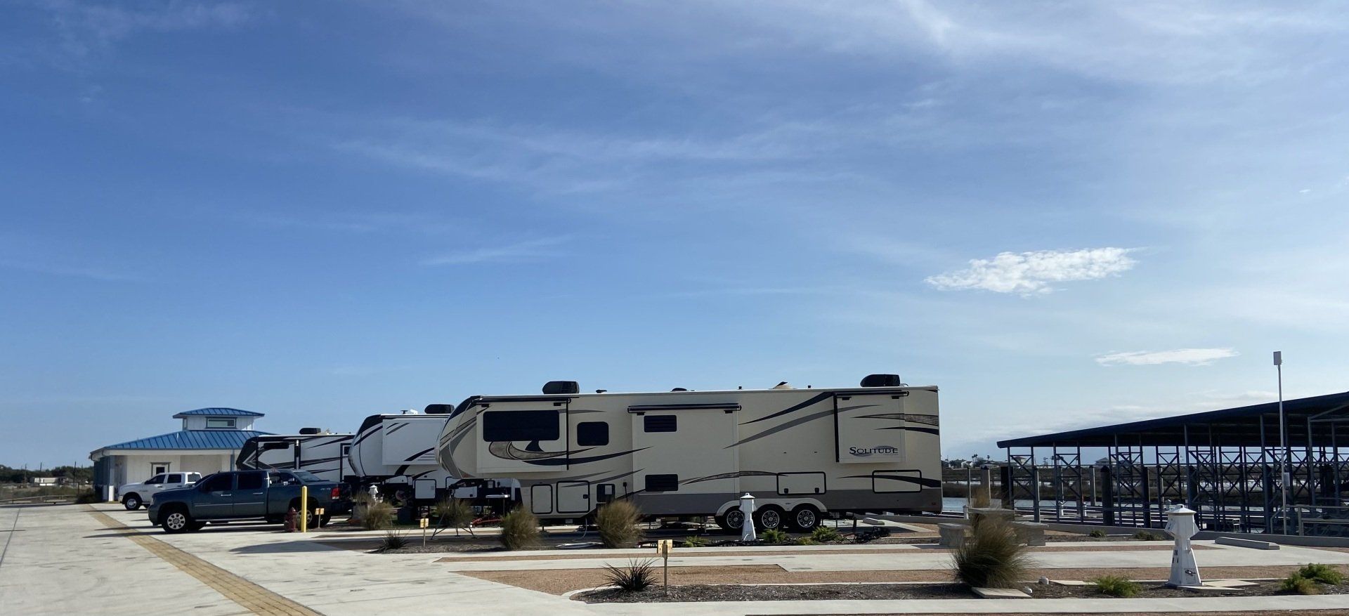 A row of rvs parked in a parking lot on a sunny day.