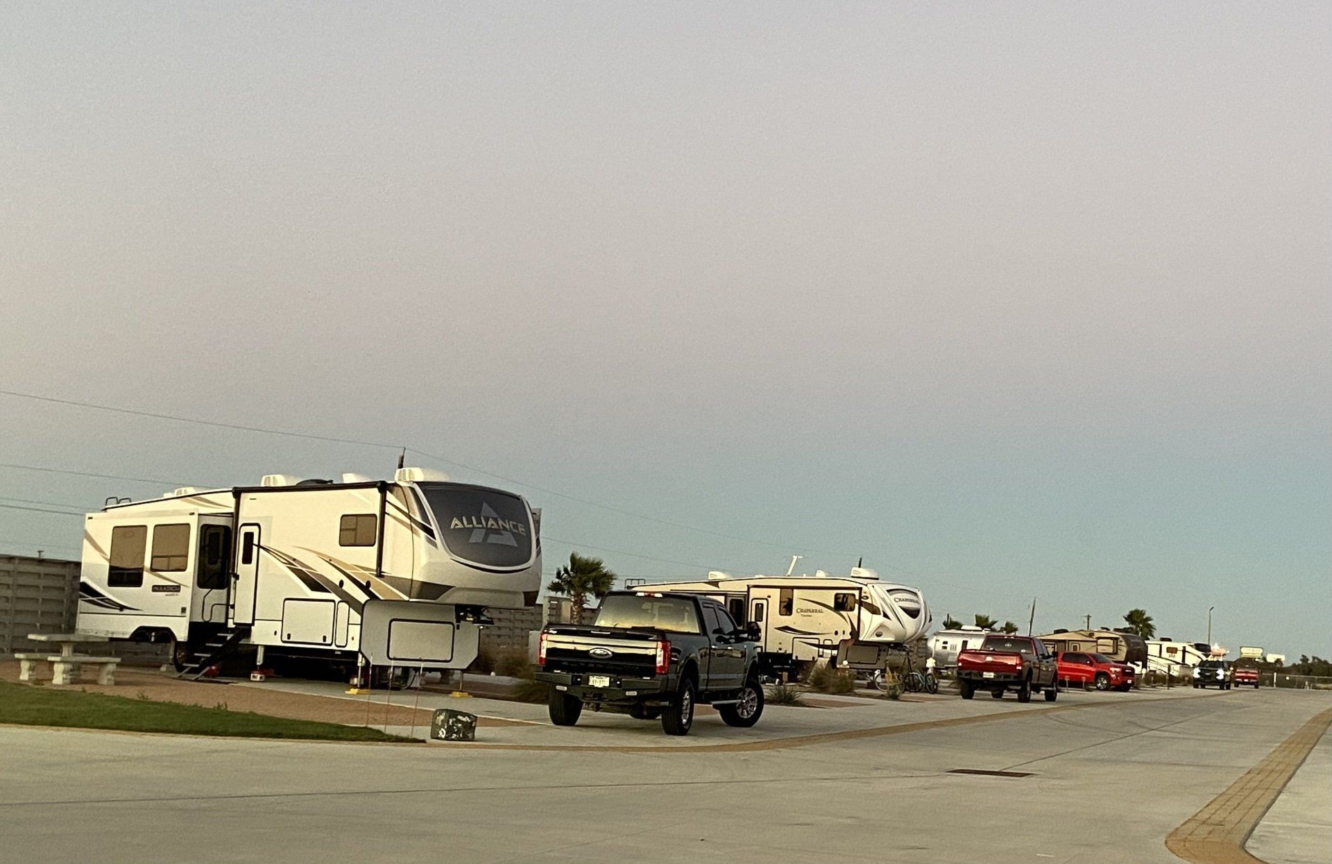A row of rvs are parked in a parking lot.